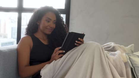 beautiful young black woman sofa relaxing happy smiling reading book blanket