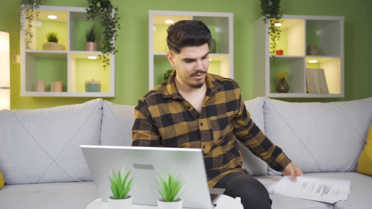 el joven que trabaja entre documentos y computadora portátil termina su trabajo y se relaja.