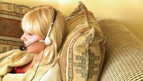 Ruhige-Frau,-Die-Mit-Headset-Spricht-Und-Auf-Dem-Bett-Liegt