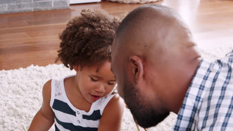 young black girl playing instrument with dad in sitting room