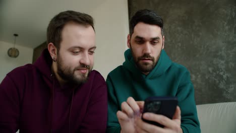 gay couple hold smartphone read good news amazed by mobile online bet or news and hug