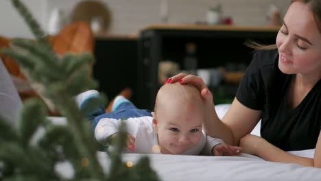 eine glückliche, liebevolle familie. mutter spielt mit ihrem baby im schlafzimmer.