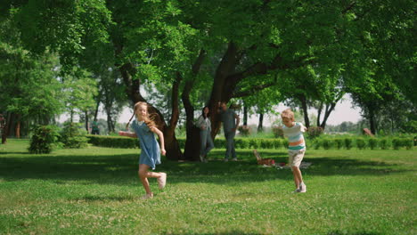 Active-girl-running-around-boy-on-green-grass.-Playful-kids-have-fun-on-picnic.