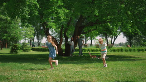 active girl running around boy on green grass. playful kids have fun on picnic.