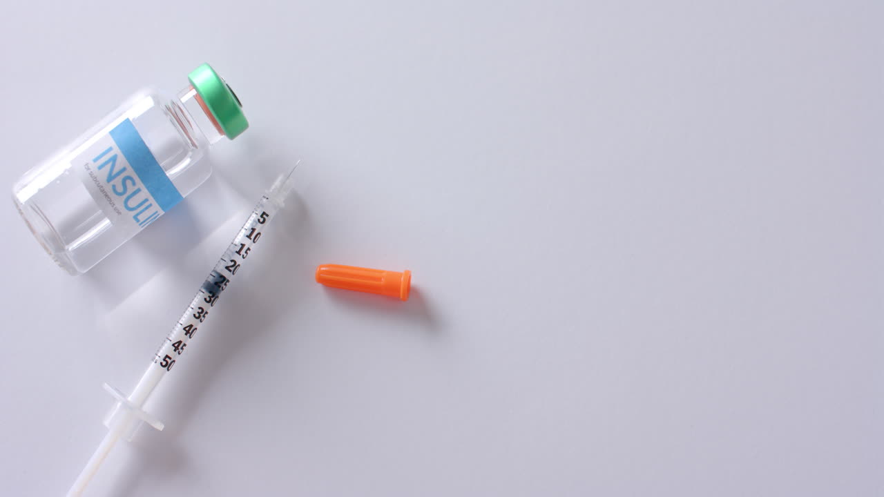 cerrar el vial de insulina y la jeringa sobre un fondo blanco con espacio de copia, cámara lenta.