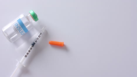 close up of insulin vial and syringe on white background with copy space, slow motion
