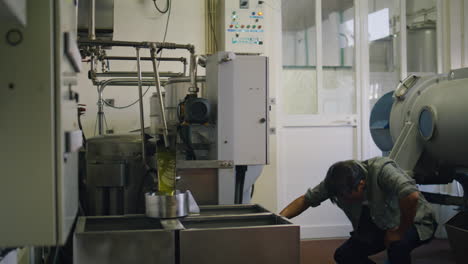 serious man turning press machine at fabric closeup. worker producing olive oil