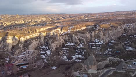 Aerial-Drone-View-of-Goreme-Turkey,-Edge-of-City-Limits:-Scenic-Town-Nestled-in-the-Heart-of-Cappadocia's-Unique-Rock-Formations---Fairy-Chimney-House:-Downtown-Göreme,-Nevşehir-Türkiye