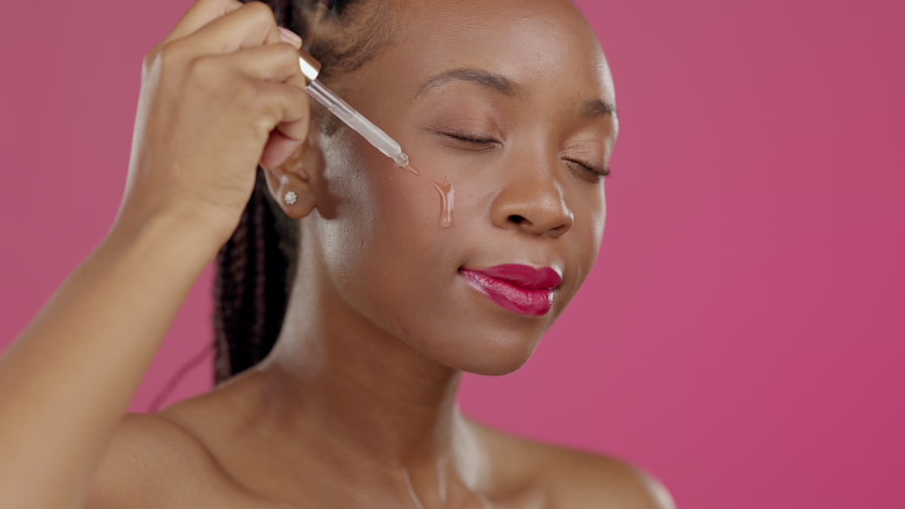 modelo, rostro y suero de belleza en rosa aislado