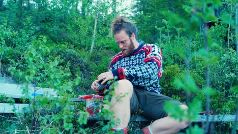retrato de un hombre preparando un bocadillo mientras hace una caminata en el bosque escandinavo