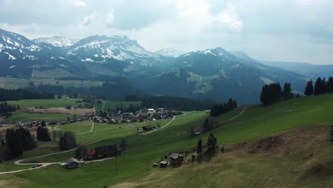 small-mountain-village-in-switzerland-countryside-entlebuch,-snow-covered-mountain-landscape,-aerial-view-of-swiss-mountains