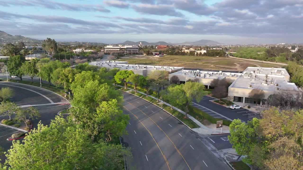 east brier drive san bernardino california temprano en la mañana amanecer iluminación en la exuberante vegetación verde con un cielo azul y edificios comerciales en el fondo dolly aéreo