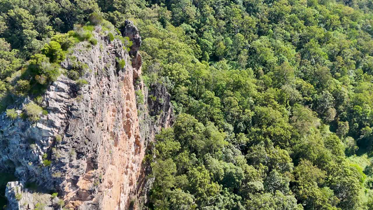 Drone captures Nimbin Rocks surrounded by dense eucalyptus forest under bright daylight, showcasing natural beauty and geological formations