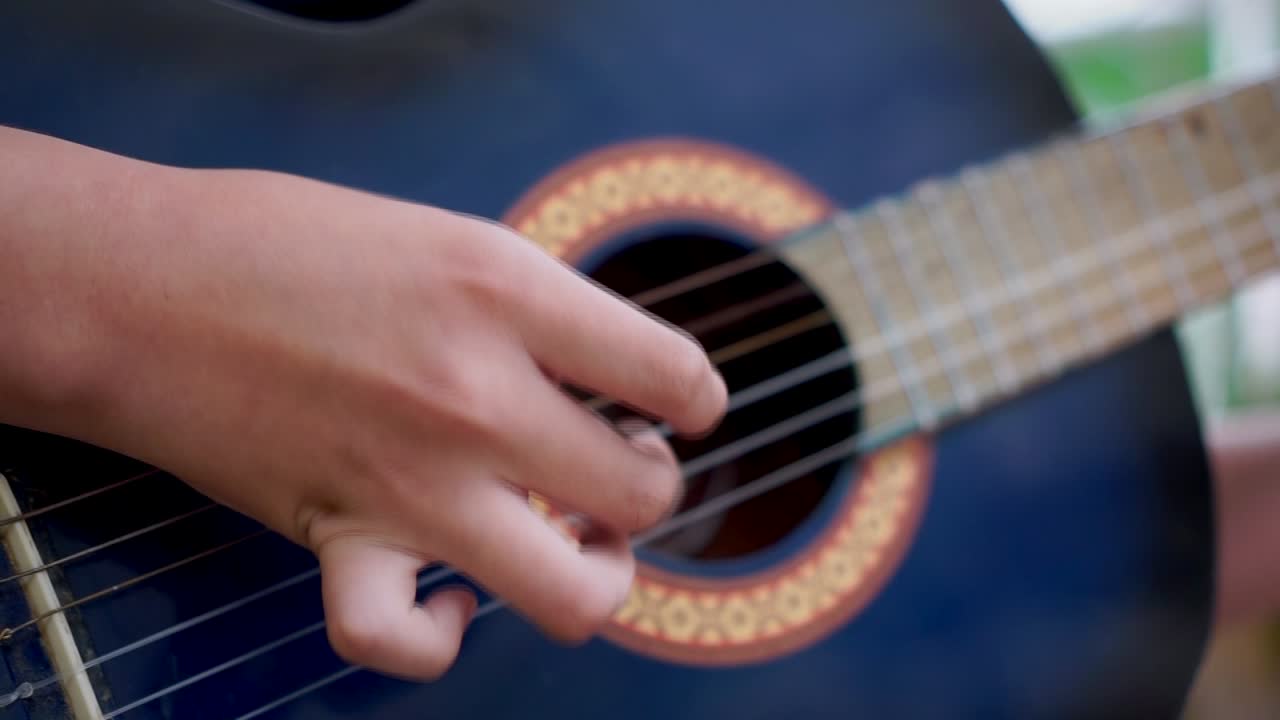 cerca en el dedo del niño recogiendo cuerdas de una guitarra acústica azul