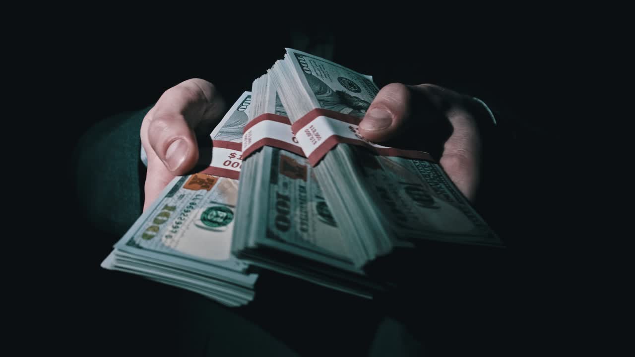 Three Stacks of 10000 American Dollars Bundles in Male Hands on Black Background