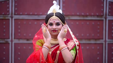 shy and happy indian bengali bride peeks between her hands and smiles