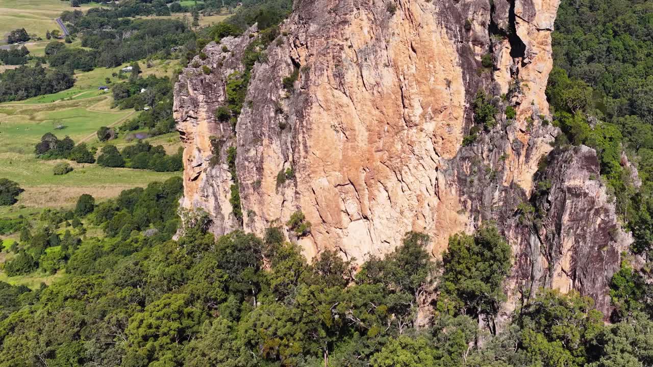 Aerial footage captures the majestic Nimbin Rocks surrounded by lush greenery under bright daylight in New South Wales