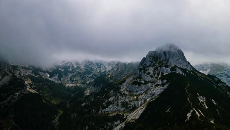 drone hyper lapse of beautiful mountains covered in clouds up in the slovenian mountains in the alps with left to right drone movement and clouds moving