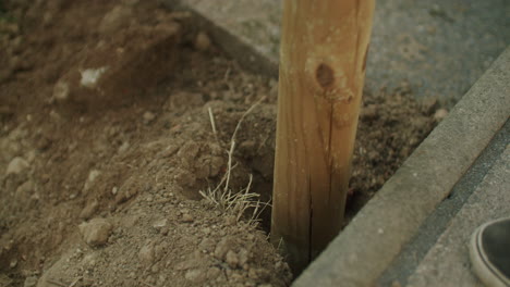 handheld close up shot of a female ramming a pole into the earth