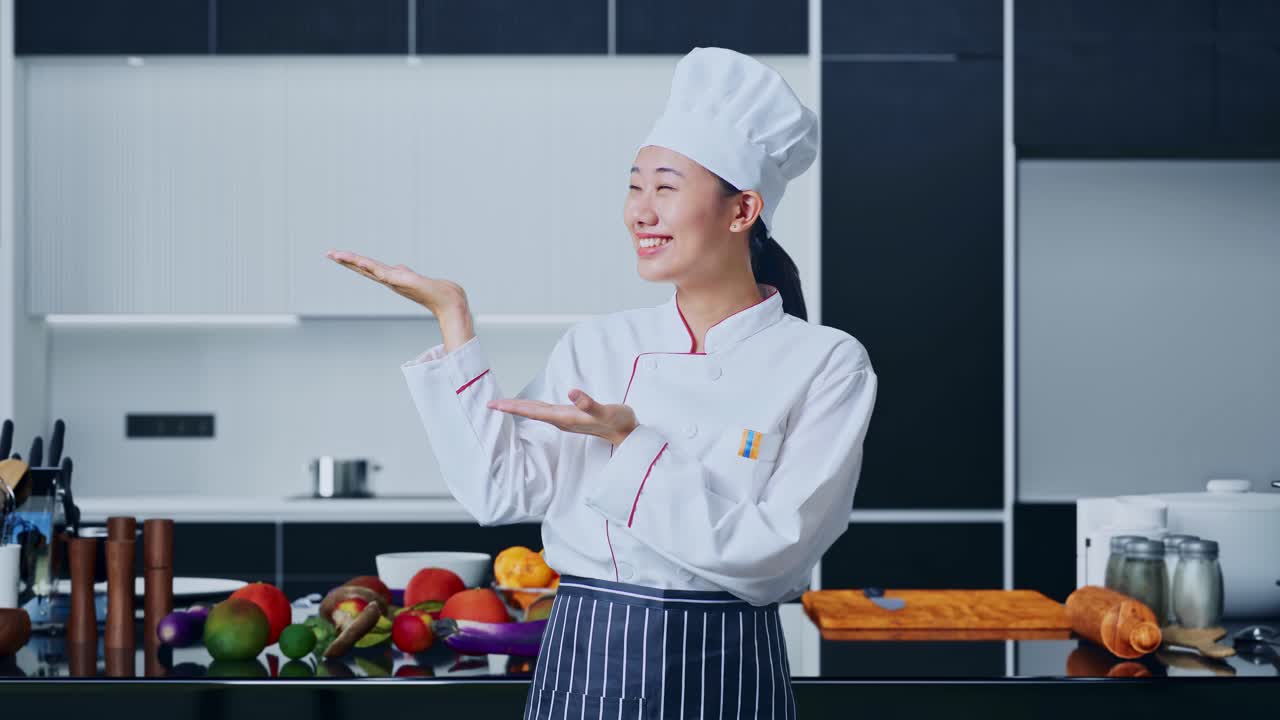 아시아 여인 요리사 가 미소 짓고 집 주방 의  을 가리키고 있다