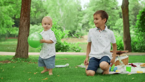 two brothers spending time in summer park. siblings playing with ball outdoors