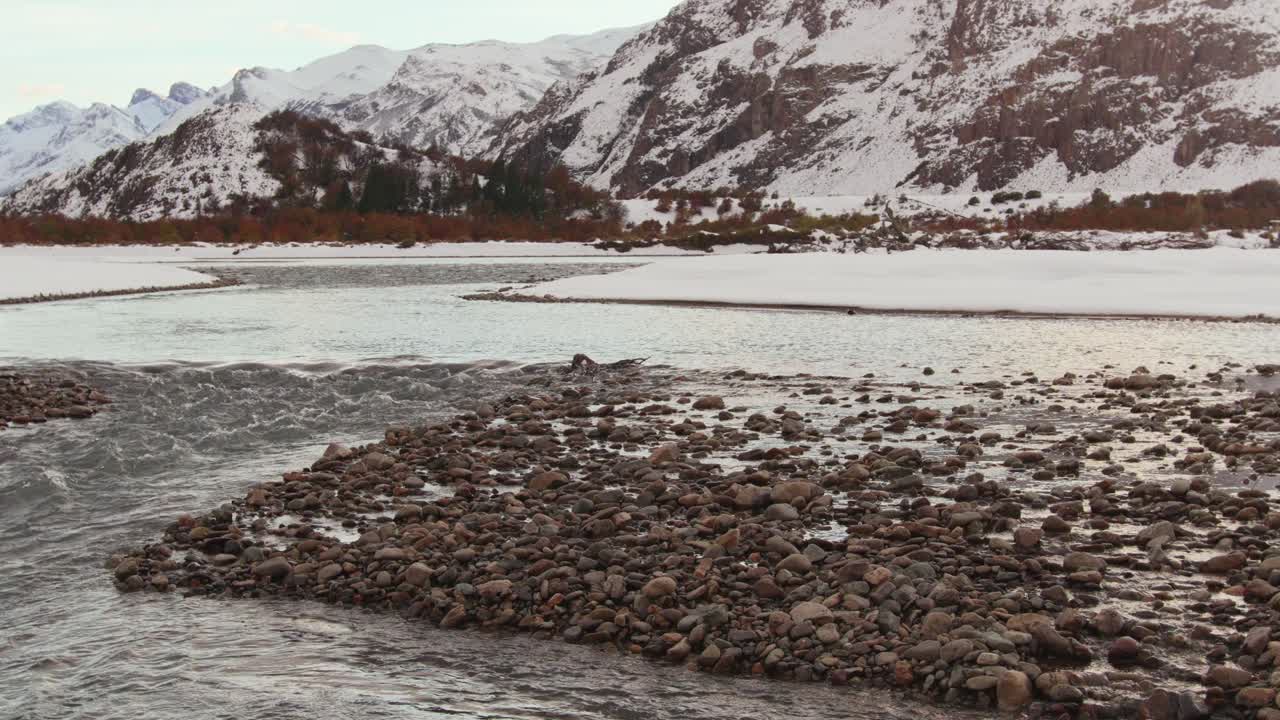 Patagonia in winter with snow-covered land, river, and mountain peaks ...