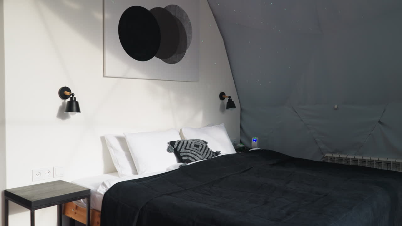 dormitorio en bungalow de glamping para turistas. acogedora cama doble de madera con almohadas suaves en una habitación con paredes blancas para turistas que aprecian el confort y el descanso en la naturaleza