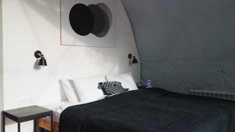 bedroom in glamping bungalow for tourists. cozy wooden double bed with soft pillows in room with white walls for tourists appreciating comfort rest in nature