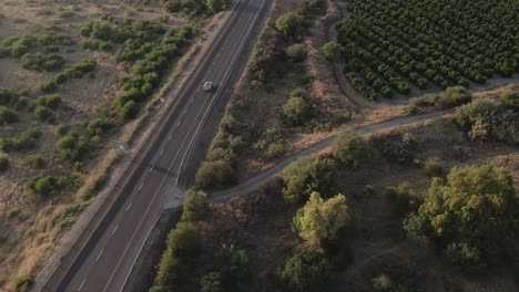 Single-car-driving-on-Golan-heights-road-as-drone-tilt-up,-revealing-vast-open-landscape