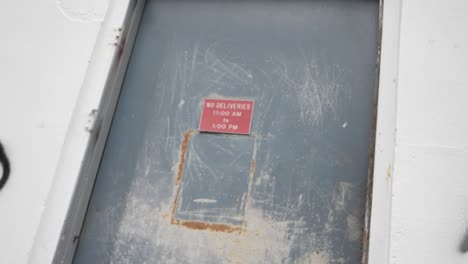 slow motion push in on a creepy red no deliveries sign on an abandoned warehouse door