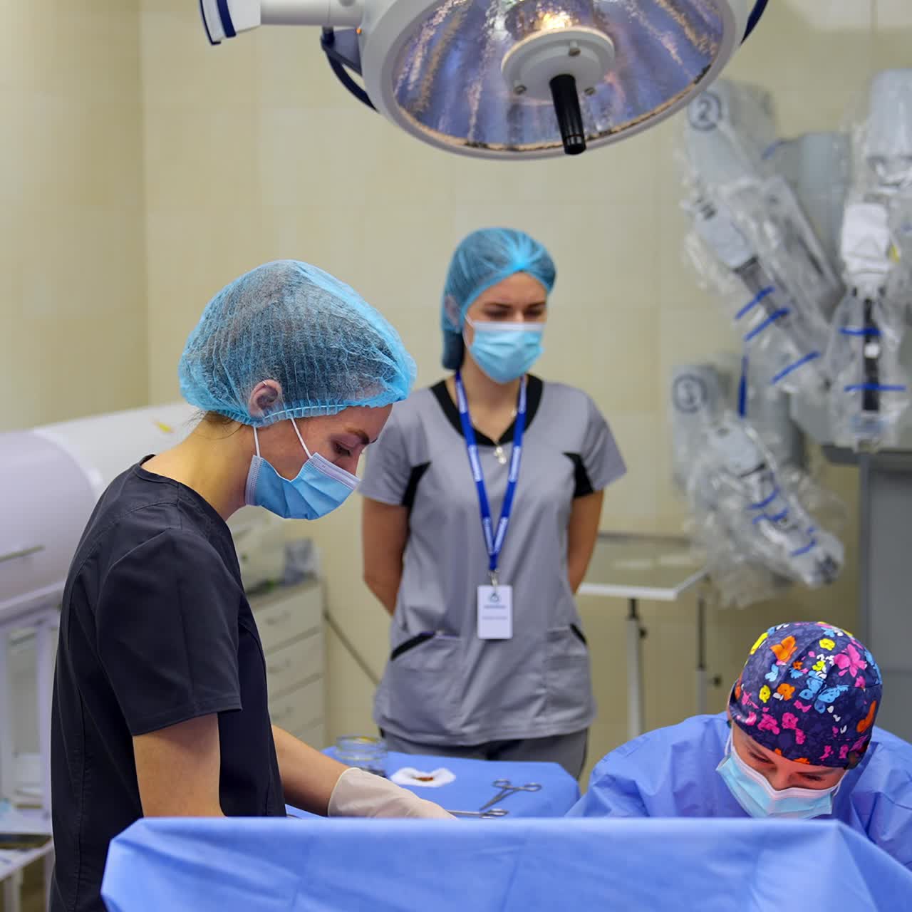 Female medical professionals working in the modern surgical theatre. Surgeon performing surgery sitting near patient. Two nurses assisting