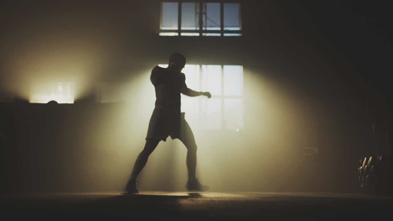 Man boxing in a dark gym