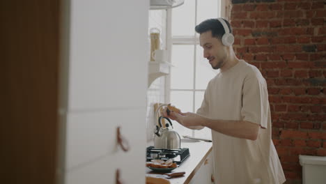 man making toast in the kitchen while listening to music