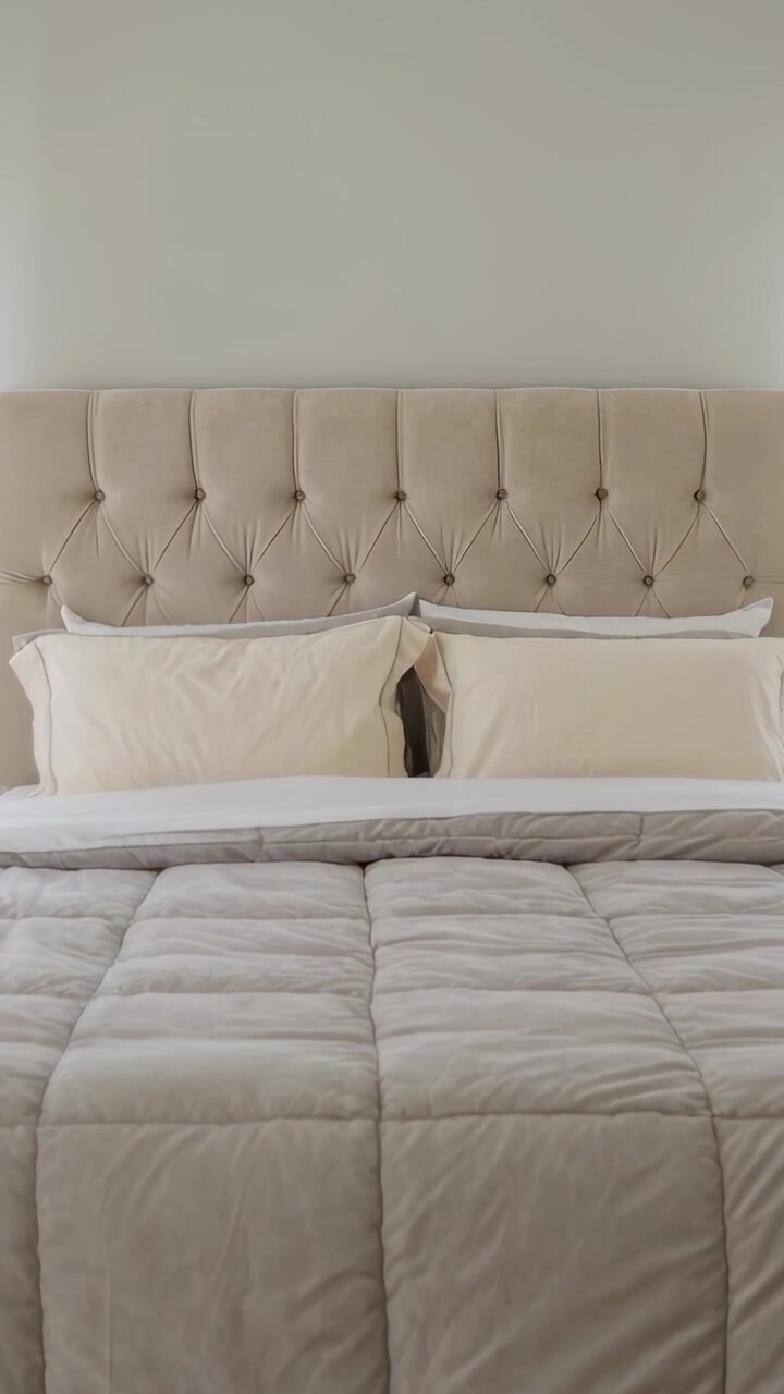 Video verticale: Telecamera che si sposta rivelando un letto rifatto in camera da letto, mostrando testiera capitonné e cuscini.