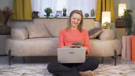 Woman-looking-at-laptop-counting-money.