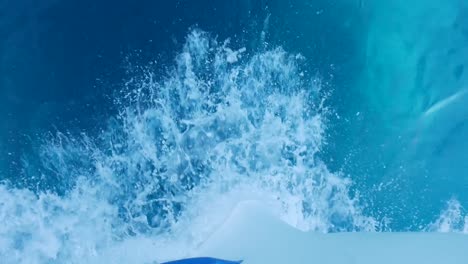 view looking over the front of a speeding boat at the waves and wake in the water