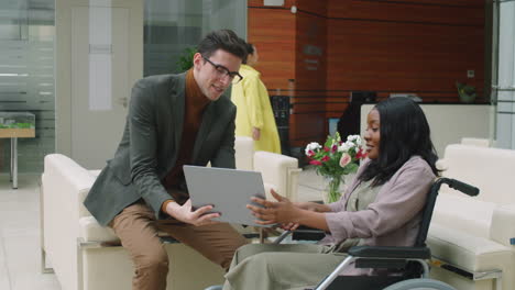 businessman discussing project on laptop with disabled female colleague