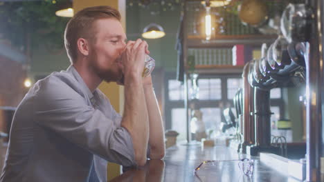 Hombre-Sentado-En-El-Bar-Bebiendo-Solo-Con-Un-Vaso-De-Whisky-Hablando-Por-Teléfono-Móvil