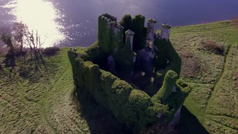 Toma-Aérea-Oblicua-Que-Captura-El-Castillo-De-Menlo-En-La-Orilla-Del-Río-Corrib-En-Una-Tarde-Soleada.