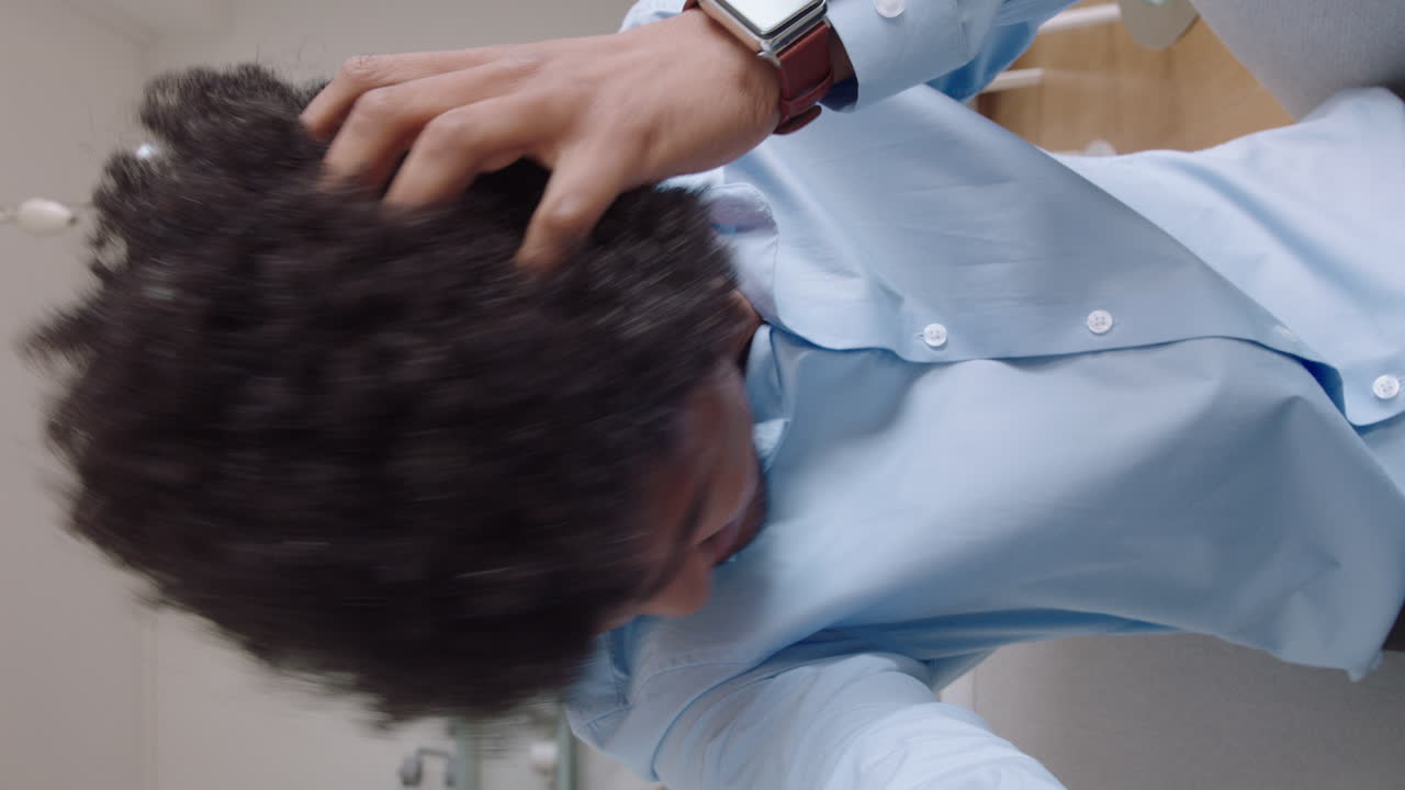 매력적인 젊은 남자가 집에서 웹캠을 사용하여 비디오 채팅을 하고 헤어스타일을 과시하고 채팅하고 라이프 스타일을 공유하고 수직 화면에서 온라인 커뮤니케이션을 즐기고 있습니다.