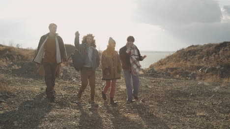 group of teenage friends are talking and walking in a mountain path on a windy day 2