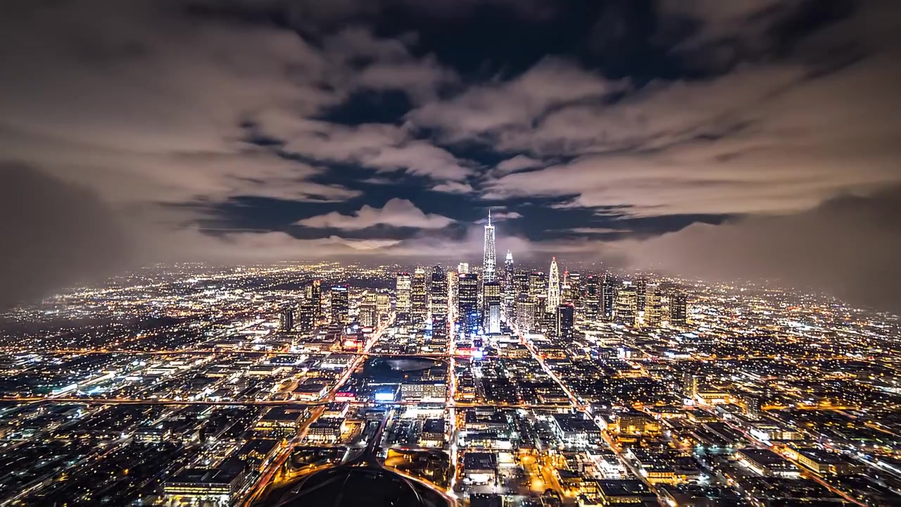 Cinematic aerial view of city lights emerging through night fog