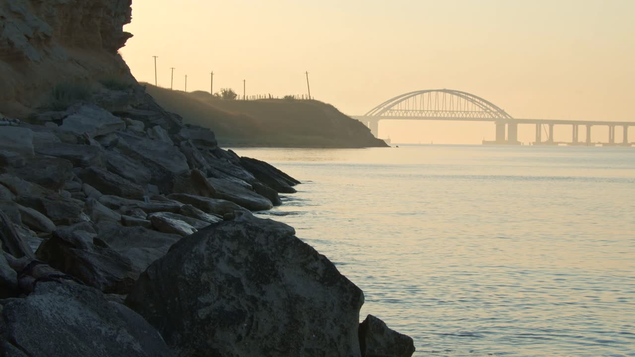 다리와 바위 해안선이 있는 강 위의 해가 뜨는 모습