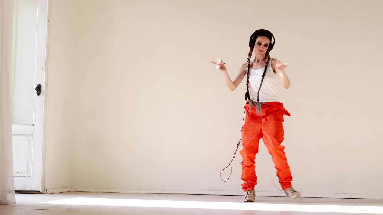 a woman with pigtails listens to music with headphones and dancing