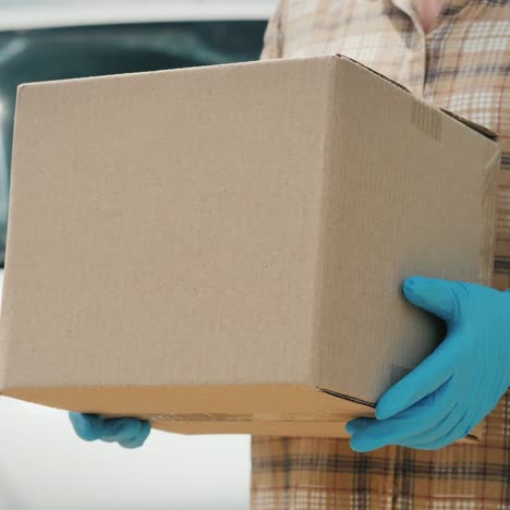 a delivery service worker holds a parcel standing near a van 1