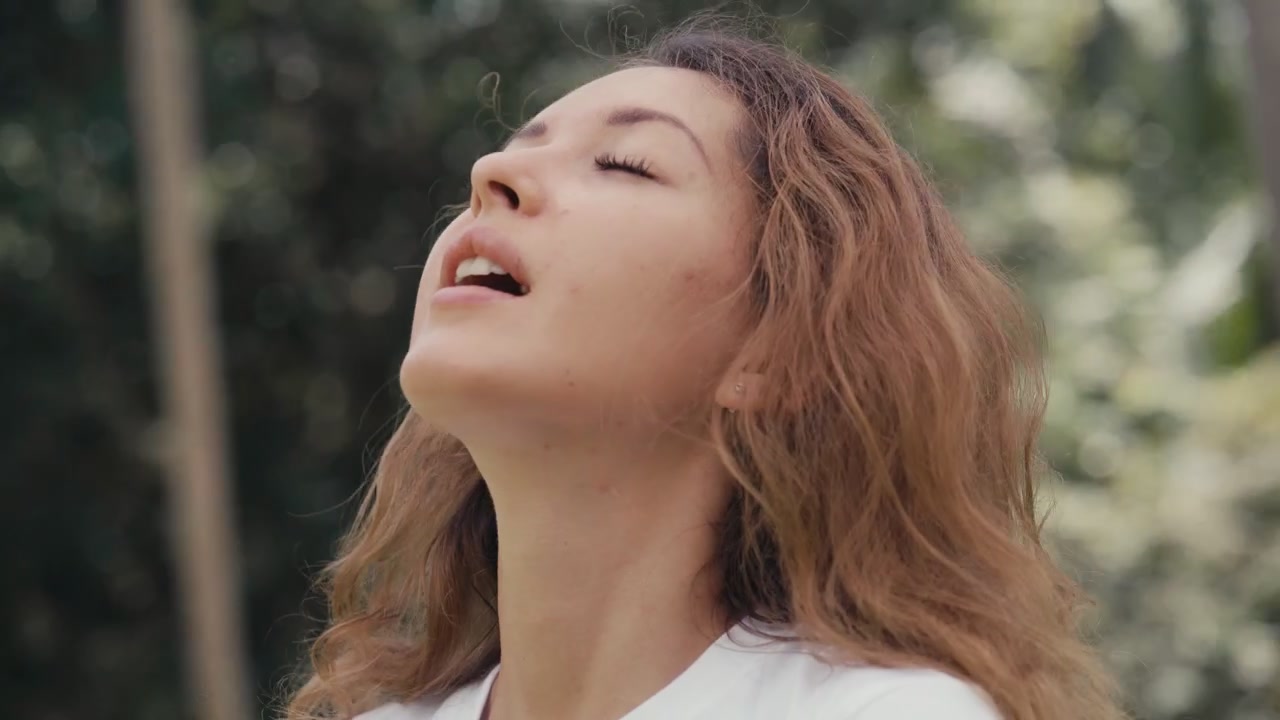 Giovane donna che si toglie la mascherina e respira aria fresca all'aperto