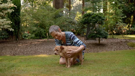 older woman playing with, petting cute small dog in yard, loving, joy