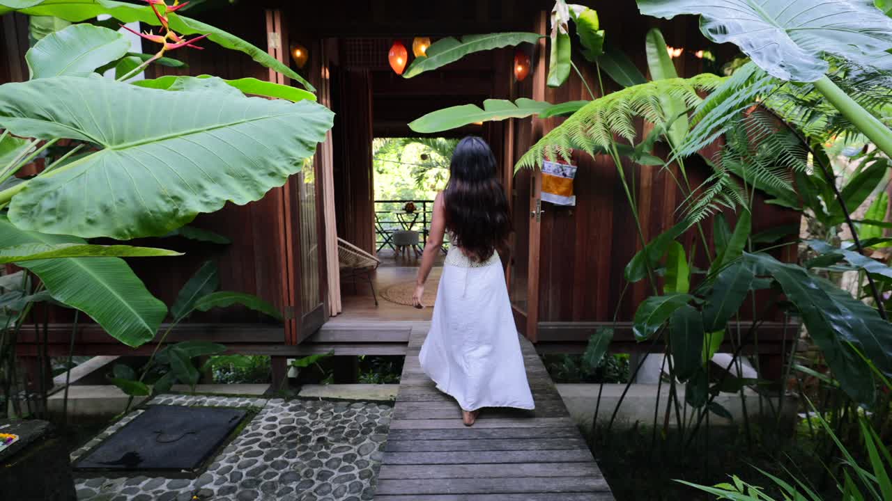 バリ島の自然豊かな庭園ヴィラで、白いドレスを着たアジア人女性がくるくる回るスローモーション