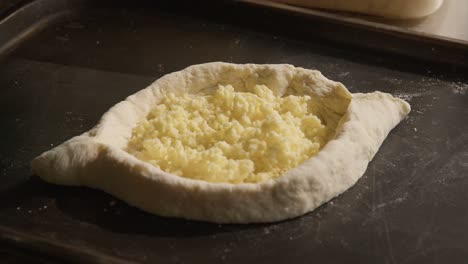 georgian cheese plate - hachapuri, chef adding cheese with wooden spoon