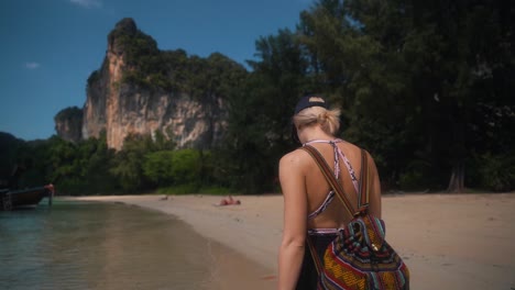 vista de uma jovem mulher caucasiana caminhando na praia na bela ilha paradisíaca de phi phi, província de krabi, mar de andaman, tailândia